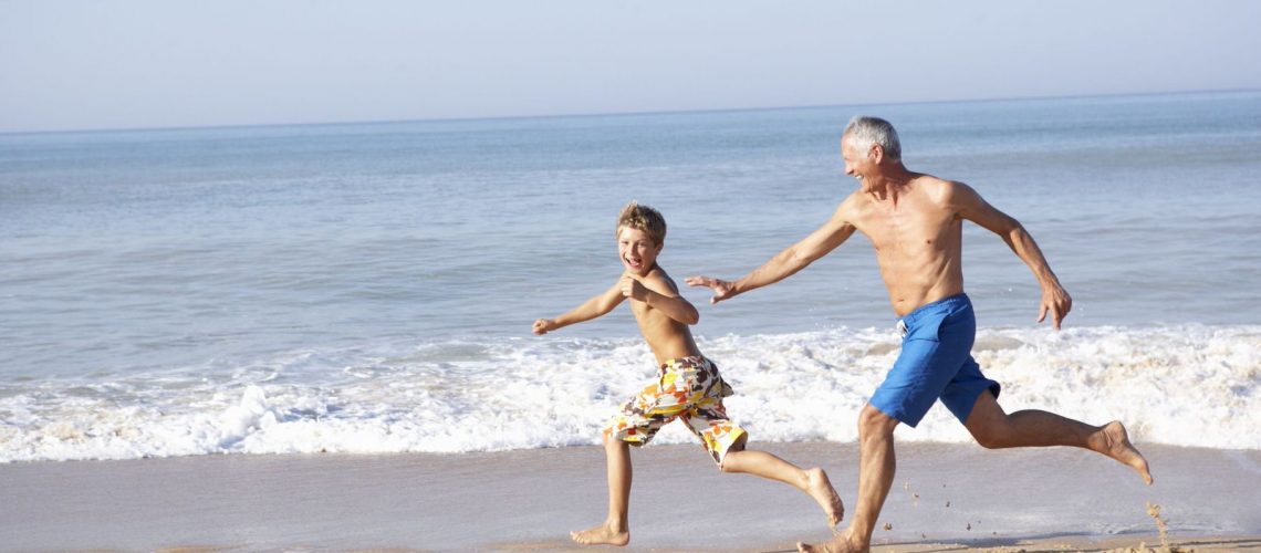 9195323 - grandfather chasing young boy on beach